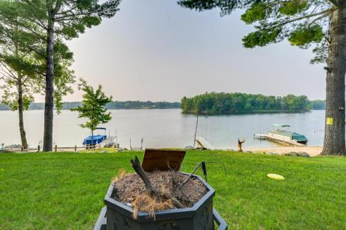 a fire pit in the grass next to a lake at Luxe Waterfront Home with Private Lake Access! in West Branch