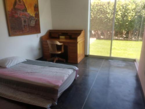 a bedroom with a bed and a desk and a window at Casa en Cuernavaca para fin de semana in Cuernavaca