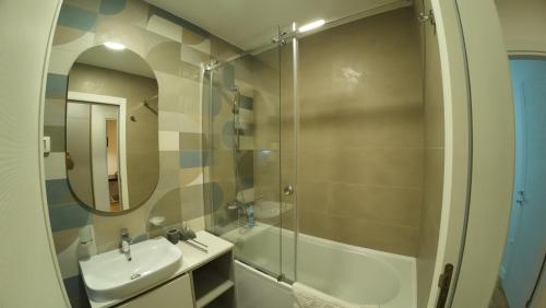 a bathroom with a sink and a shower with a mirror at Apartments Eagle, close to center Podgorica, free parking, available transport in Podgorica
