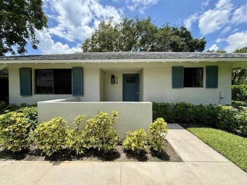 a small white house with blue shutters on it at PGA National Paradise in Palm Beach Gardens