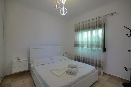 a white bedroom with a bed and a shower at Loris Apartment in Sarandë
