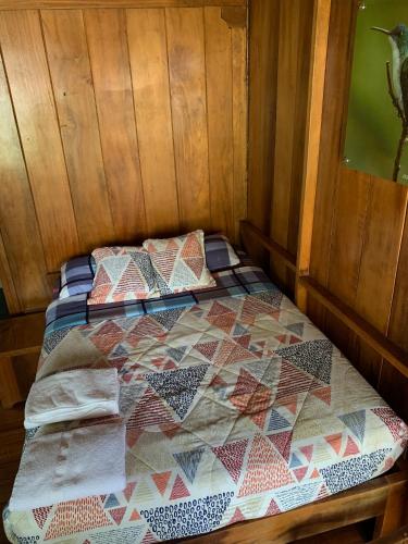 a bed in a room with a quilt on it at El Descanso in Mindo