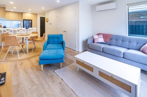 a living room with a blue couch and a table at Modern 2 Bed 2 Bath Opposite Hagley Park in Christchurch