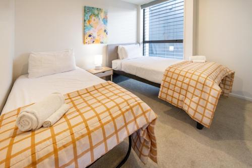 a bedroom with two beds and a window at Modern 2 Bed 2 Bath Opposite Hagley Park in Christchurch