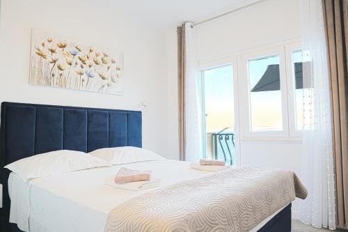 a bedroom with a bed with a blue headboard and a window at Apartments with parking space Marusici, Omis - 657 in Mimice