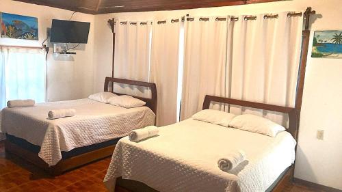 a room with two beds and a television in it at Coconut Tree West Bay in West Bay