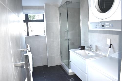 a white bathroom with a sink and a shower at 6 on Adams in Mount Maunganui