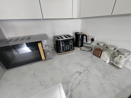 une cuisine avec un comptoir avec un grille-pain et un micro-ondes dans l'établissement Stylish Madison Apartment with Balcony - FREE Car Parking - Hemel Hempstead Town Centre, à Hemel Hempstead