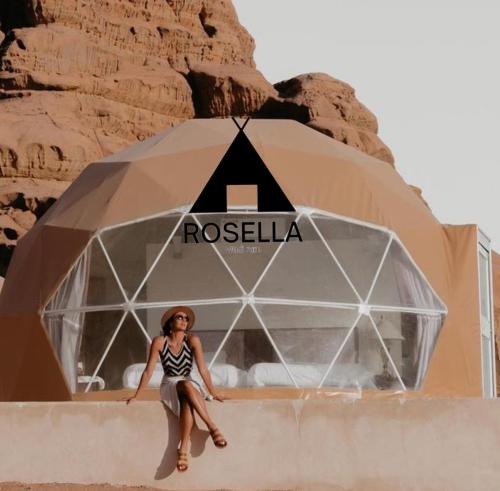 a woman is sitting in front of a building in the desert at ROSELLA Wadi Rum in Disah