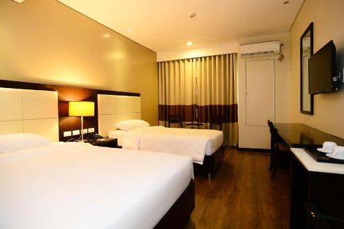 um quarto de hotel com duas camas e uma televisão de ecrã plano em Ever O Business Hotel em Zamboanga