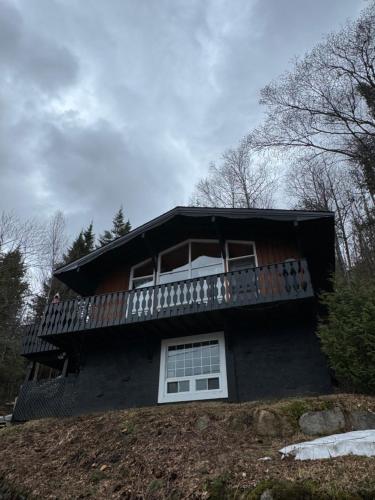 a house with a balcony on top of a hill at Chalet Alpin Suisse Au Bord Du Lac in Morin Heights