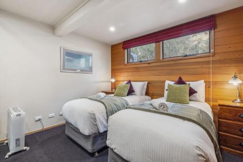 two beds in a room with wood paneling at Nowhere Lodge in Crackenback