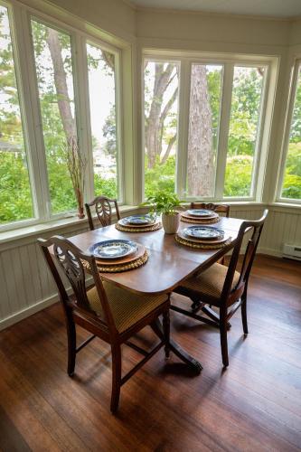 a dining room with a table and chairs and windows at Wilder House Berkshires in Sheffield