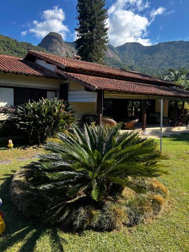 a palm tree in front of a house with mountains at Recanto dos Vianas in Teresópolis