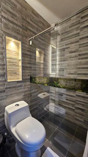 a bathroom with a toilet and a glass shower at Waldor's Hotel Boutique in Leticia
