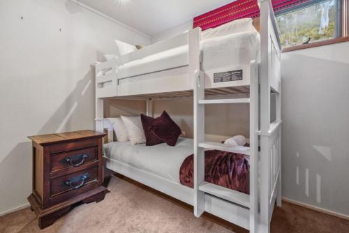 a white bunk bed in a room with a night stand at Nowhere Chalet in Crackenback