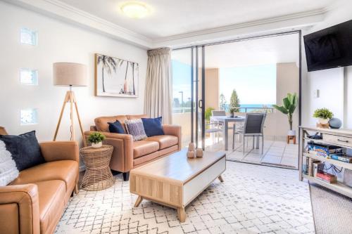 a living room with a couch and a table at Tides and Tranquility at Kings Beach in Caloundra