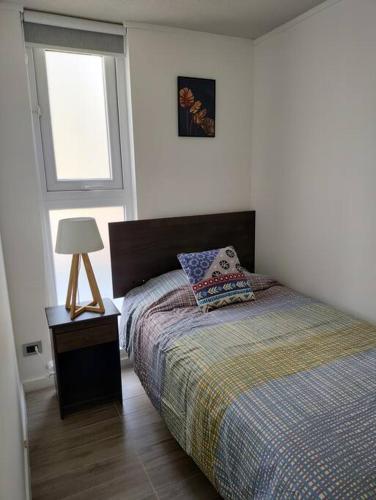 a bedroom with a bed and a lamp and a window at Descanso en Isla teja in Valdivia