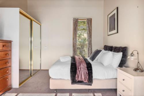 a bedroom with a bed and a dresser and a window at Nowhere Chalet in Crackenback