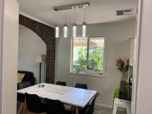a dining room with a white table and a window at Cottage BNB near the hill in Teatree Gully