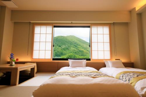 two beds in a room with a large window at Shouhakutei Azumaso in Tendo