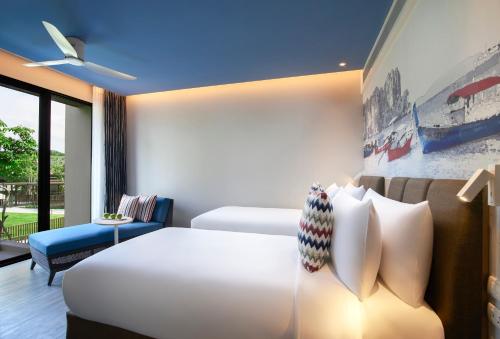 a hotel room with two beds and a couch at OZO Phuket in Kata Beach