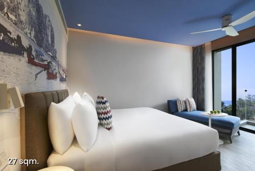 a bedroom with a large white bed with pillows at OZO Phuket in Kata Beach