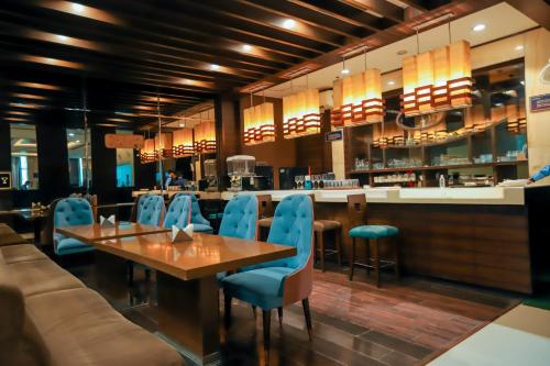 Un restaurante con una mesa de madera y sillas azules. en Bel-La Monde Hotel Chhattarpur South Delhi, en Sat Bari