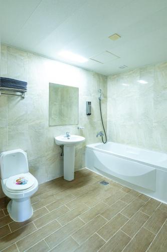 a bathroom with a toilet and a tub and a sink at Amoureux Resort in Jeju