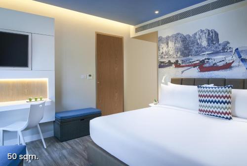 a hotel room with a large bed and a desk at OZO Phuket in Kata Beach