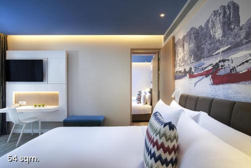 a bedroom with a bed and a desk and a sink at OZO Phuket in Kata Beach