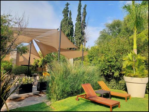 a garden with two wooden chairs and a tent at Hotel Rio Tequisquiapan in Tequisquiapan