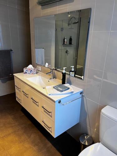a bathroom with a sink and a mirror and a toilet at Penzance Cottage Glenelg in Glenelg