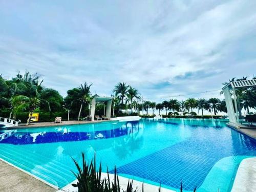 a large blue swimming pool with palm trees in the background at Studio Seaview Jomtien floor12 23sqm in Jomtien Beach