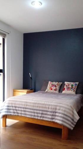a bedroom with a bed with a blue wall at Encantador y equipado en el corazón de la CDMX in Mexico City