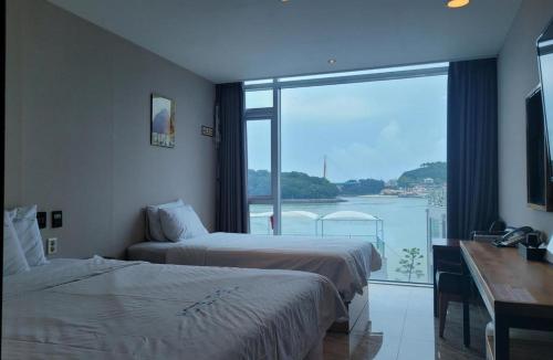 a hotel room with two beds and a large window at Hotel The L in Yeosu