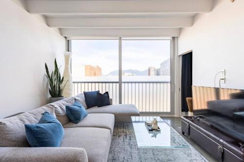 a living room with a couch and a large window at Cozy 1BR with AC, Chinatown, Rogers Arena, Seawall in Vancouver