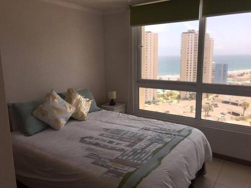 a bedroom with a bed and a large window at Departamento frente a Casino Enjoy in Coquimbo