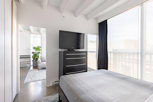 バンクーバーにあるCozy 1BR with AC, Chinatown, Rogers Arena, Seawallのベッドと薄型テレビのある寝室