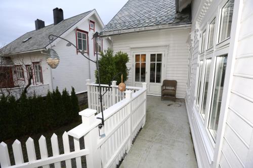 a white house with a white fence and a porch at Alnes Gård in Ålesund