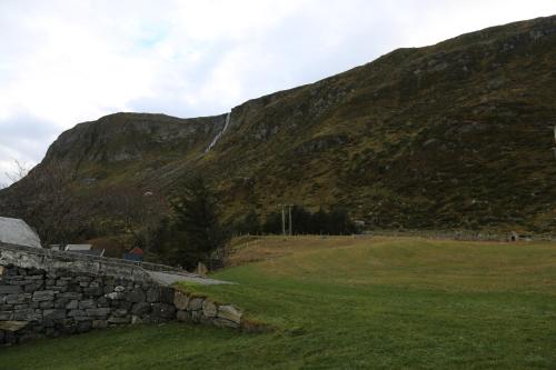 a mountain with a stone wall in front of a field at Alnes Gård in Ålesund