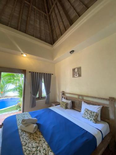 a bedroom with a large blue bed with a window at Mango 5 Hotel in Amed