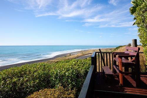 a bench sitting on the side of a beach at Surfwatch House in Kaikoura