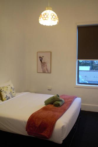 a bedroom with a bed with a blanket and a window at The Caledonian Hotel Wonthaggi in Wonthaggi
