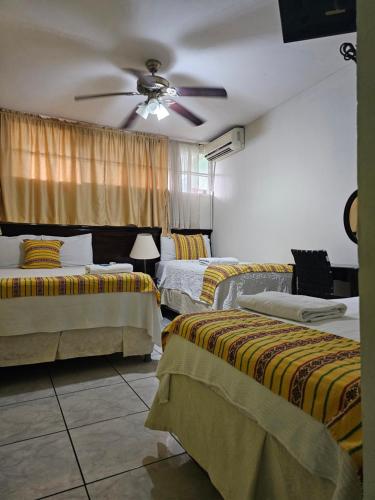 a bedroom with two beds and a ceiling fan at Hotel San Jose Hostal in San Salvador
