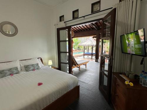 a bedroom with a bed and a television and a patio at Bale Solah Lombok Holiday Resort in Senggigi 
