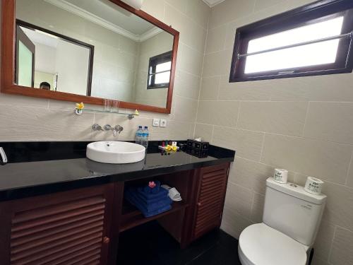 a bathroom with a sink and a toilet and a mirror at Bale Solah Lombok Holiday Resort in Senggigi 