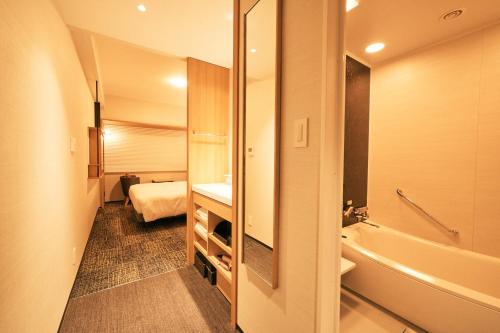 a bathroom with a tub and a sink and a toilet at Richmond Hotel Premier Kyoto Ekimae in Kyoto