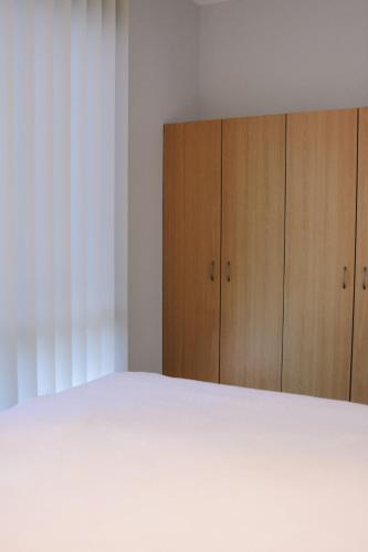 a bedroom with a white bed and wooden cabinets at Cosy Cottage in Geraldton - "Moresby Rest" in Bluff Point