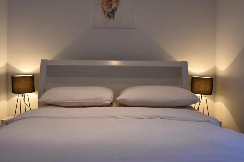 a white bed with two pillows and two lamps at Cosy Cottage in Geraldton - "Moresby Rest" in Bluff Point